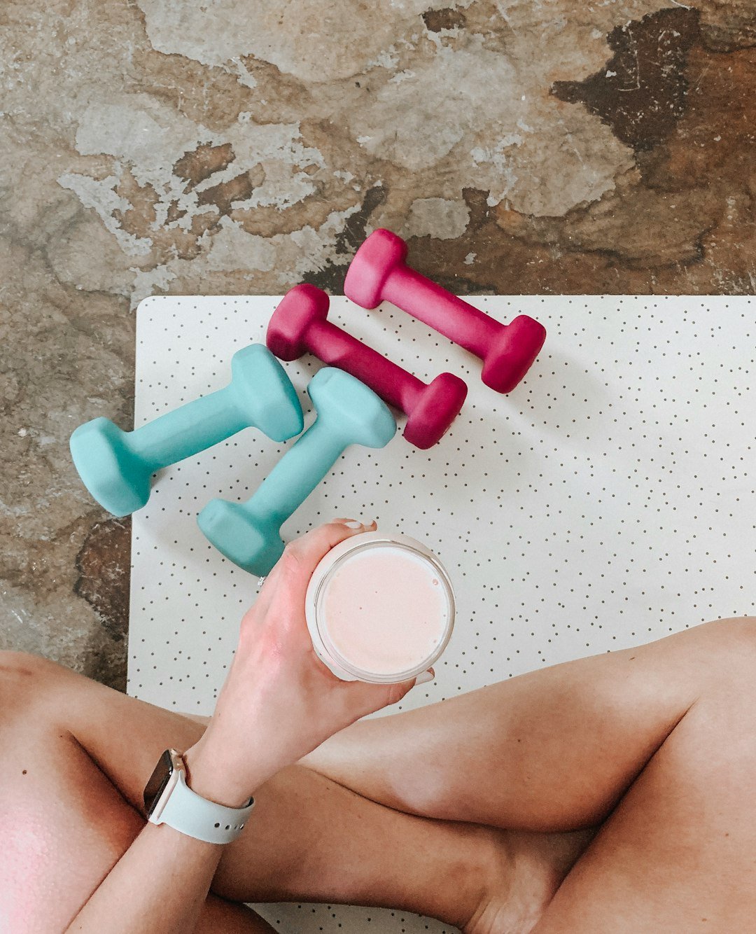 person-holding-white-liquid-filled-cup-above-two-pairs-of-dumbbells-qqvti5edc